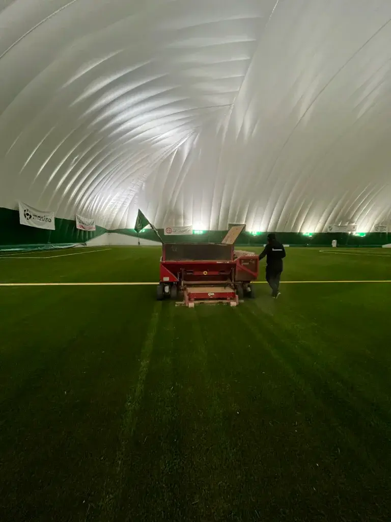 Brushing and maintenance of an artificial grass court in progress